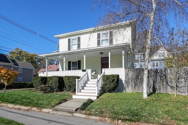 view of front facade featuring stairs, a porch, fence, and a front lawn