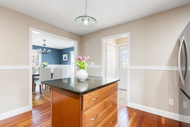 kitchen with hardwood / wood-style floors, a healthy amount of sunlight, freestanding refrigerator, and a center island