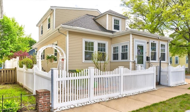 view of front of property with a fenced front yard and roof with shingles