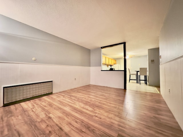 unfurnished living room with a textured ceiling and light hardwood / wood-style flooring