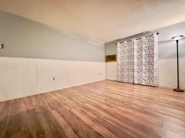 spare room with a wall unit AC and light hardwood / wood-style flooring