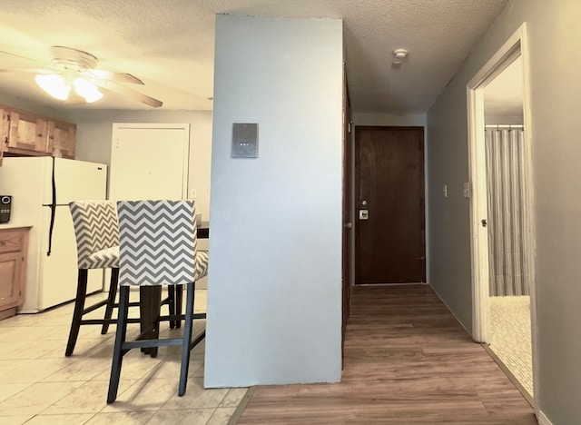 hallway with light wood-type flooring and a textured ceiling