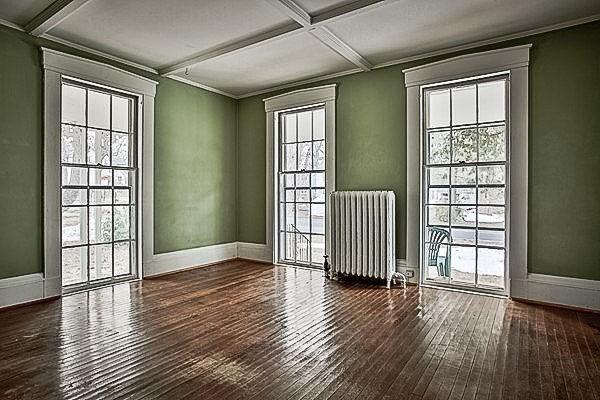 empty room with a healthy amount of sunlight, coffered ceiling, radiator heating unit, and hardwood / wood-style flooring