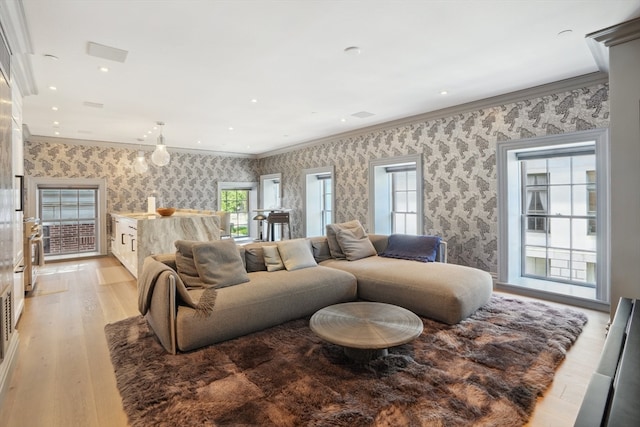 living room with plenty of natural light, ornamental molding, and light wood-type flooring