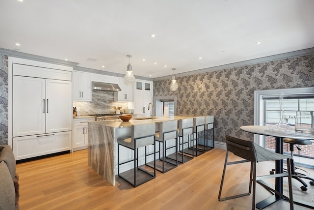 kitchen featuring white cabinetry, crown molding, extractor fan, and light hardwood / wood-style flooring