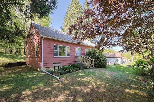 rear view of house featuring a lawn and a shingled roof