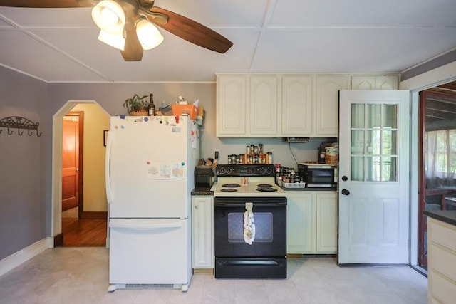 kitchen featuring freestanding refrigerator, electric range oven, stainless steel microwave, arched walkways, and dark countertops