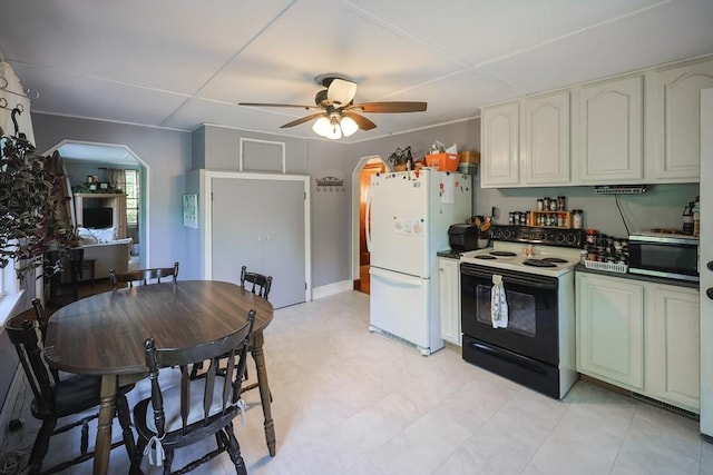 kitchen with electric range oven, stainless steel microwave, freestanding refrigerator, a ceiling fan, and dark countertops