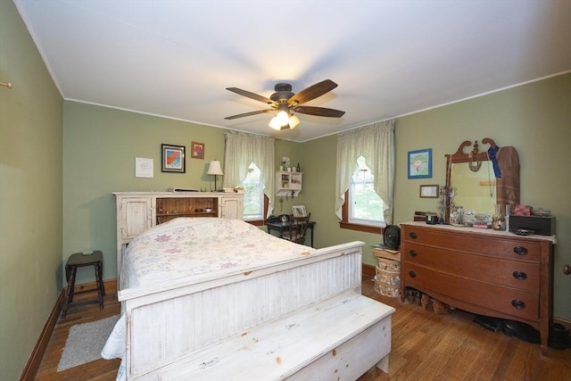 bedroom with wood finished floors, crown molding, baseboards, and ceiling fan