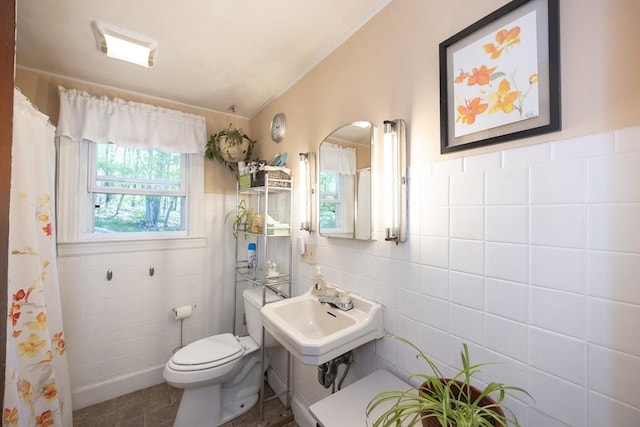 bathroom with tile walls, toilet, a sink, and curtained shower