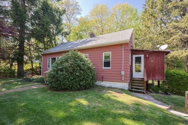 view of home's exterior featuring entry steps, a lawn, and a chimney