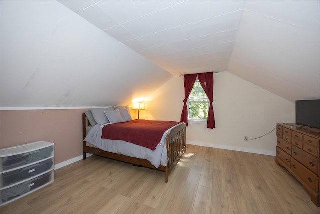 bedroom featuring light wood finished floors, lofted ceiling, and baseboards