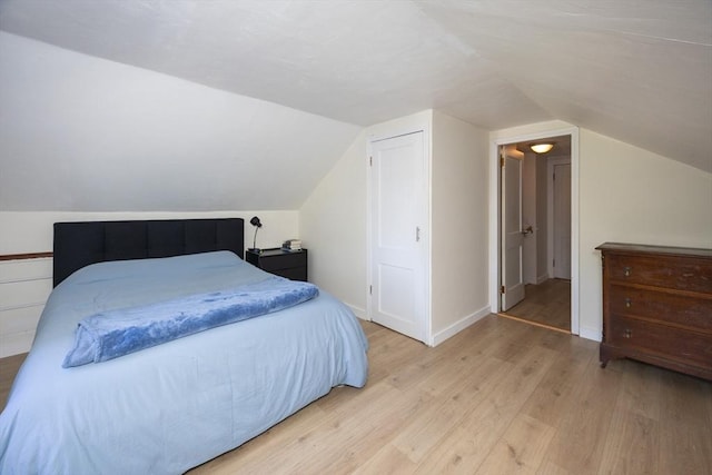 bedroom with wood finished floors, lofted ceiling, and baseboards