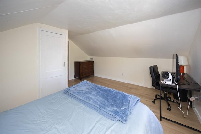 bedroom featuring vaulted ceiling, light wood finished floors, a desk, and baseboards