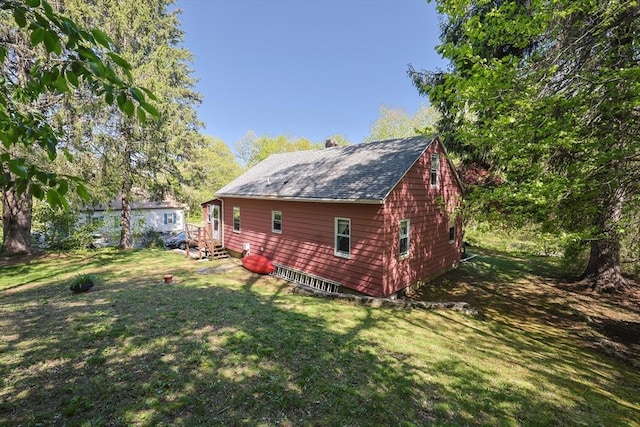 view of side of property featuring a yard, roof with shingles, and a chimney