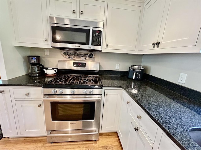 53 Washington St, Topsfield, MA 01983 - kitchen with appliances with stainless steel finishes, white cabinets, light wood-style flooring, and dark stone counters
