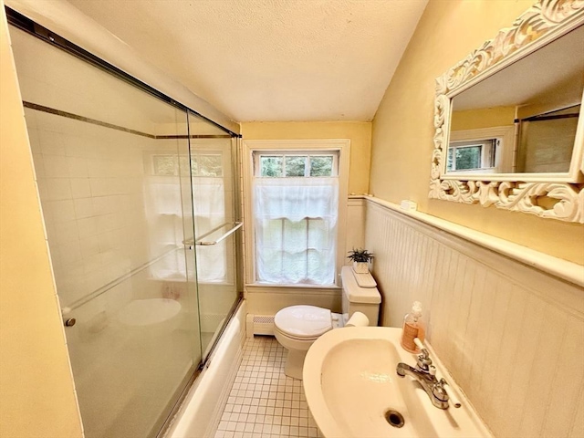 53 Washington St, Topsfield, MA 01983 - full bathroom with wainscoting, shower / bath combination with glass door, a textured ceiling, tile patterned floors, and baseboard heating