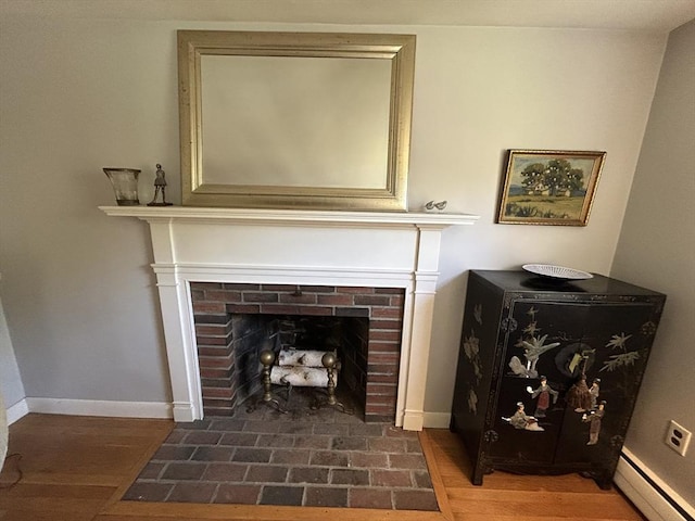 53 Washington St, Topsfield, MA 01983 - detailed view of a baseboard heating unit, a brick fireplace, and wood finished floors