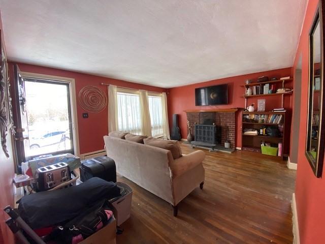 living room featuring a brick fireplace, wood finished floors, and baseboards