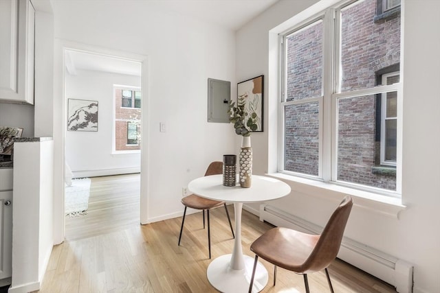 dining room featuring electric panel, light wood-style floors, and baseboards