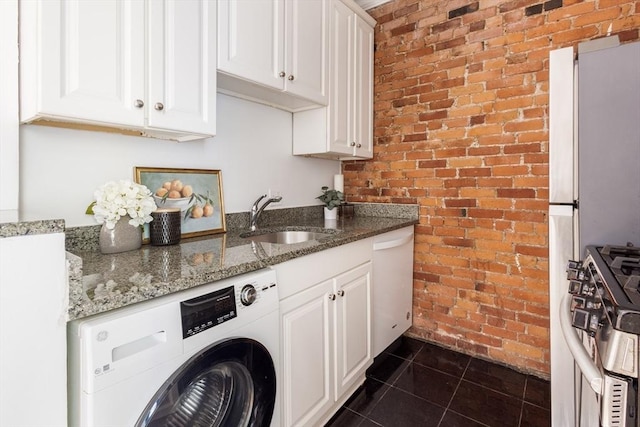 clothes washing area featuring washer / clothes dryer, brick wall, and dark tile patterned floors