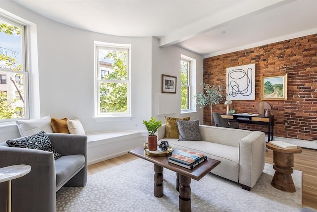 living room featuring wood finished floors, beam ceiling, brick wall, and baseboards