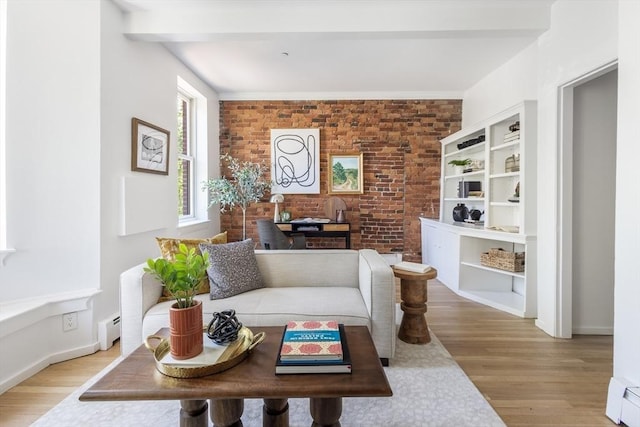 living area with brick wall, light wood-style floors, baseboard heating, and baseboards