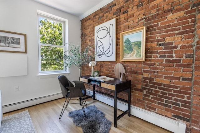home office with a baseboard radiator, healthy amount of natural light, wood finished floors, and brick wall