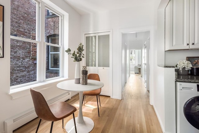 dining room featuring washer / dryer, light wood-type flooring, a baseboard heating unit, and baseboards