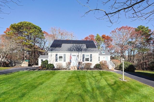 view of front of home with solar panels and a front lawn