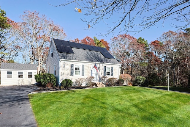 view of front of house featuring an outbuilding, solar panels, a garage, and a front yard