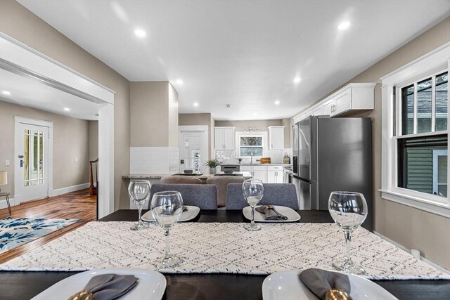 kitchen featuring stainless steel fridge with ice dispenser, recessed lighting, white cabinetry, and wood finished floors