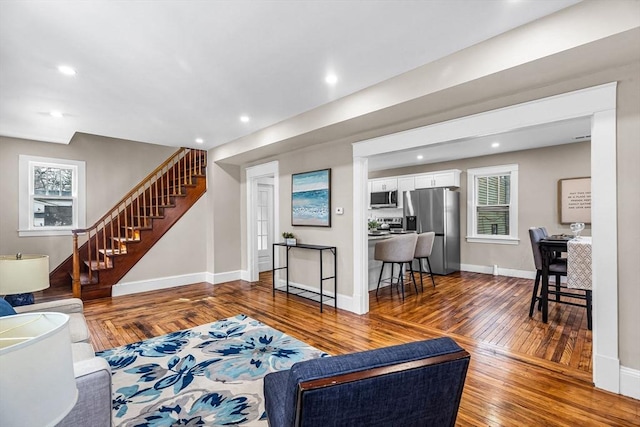 living area with wood-type flooring, baseboards, stairway, and recessed lighting