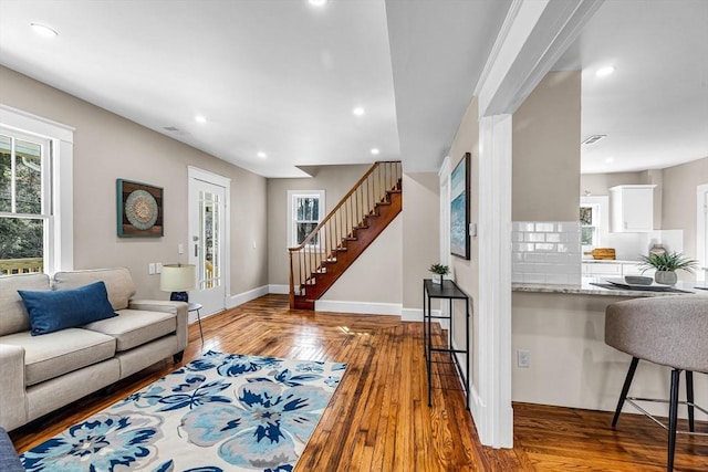 living room featuring a healthy amount of sunlight, recessed lighting, baseboards, and stairway