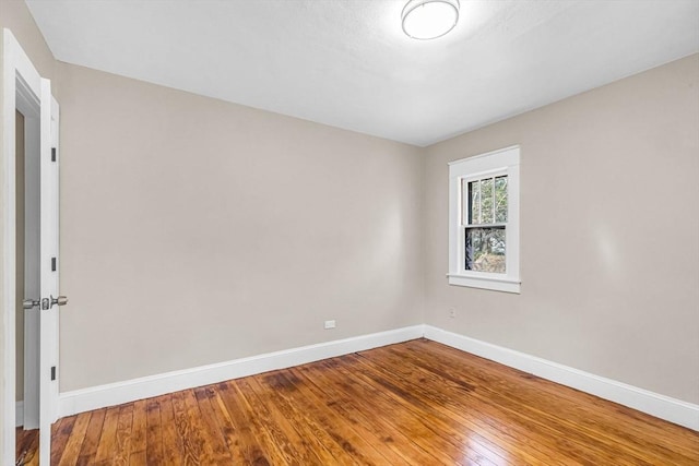 spare room with baseboards and hardwood / wood-style flooring
