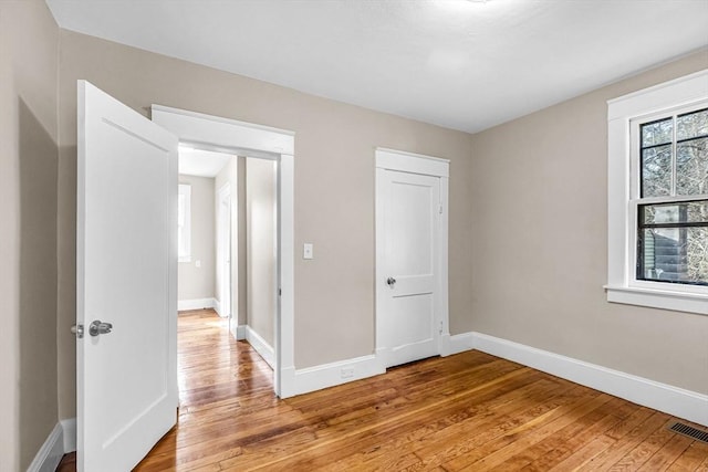 unfurnished bedroom with light wood finished floors, baseboards, and visible vents