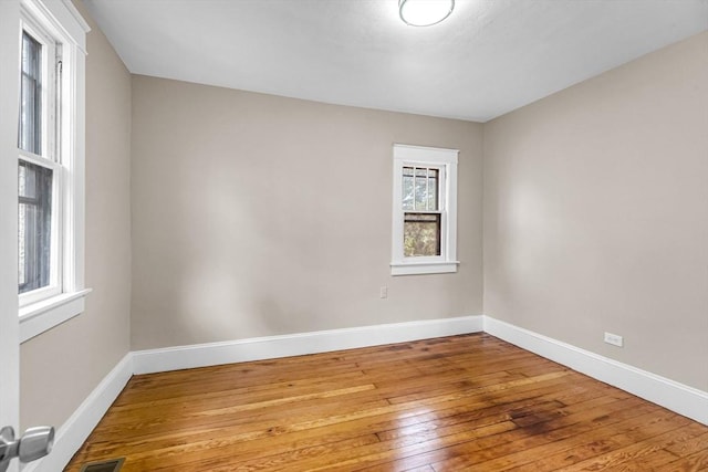 spare room featuring wood-type flooring, baseboards, and visible vents