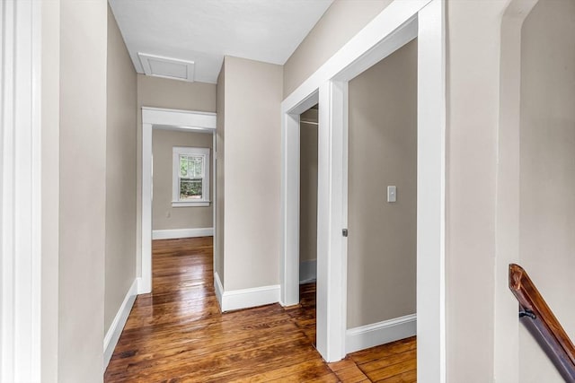 hallway featuring wood finished floors, attic access, and baseboards