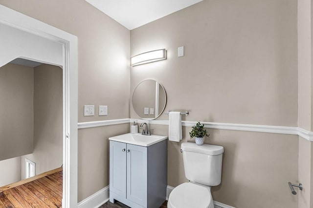 half bathroom featuring toilet, vanity, and baseboards