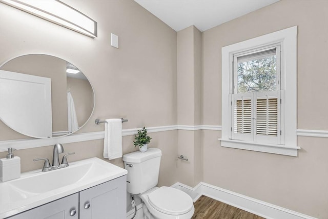 bathroom featuring toilet, baseboards, vanity, and wood finished floors