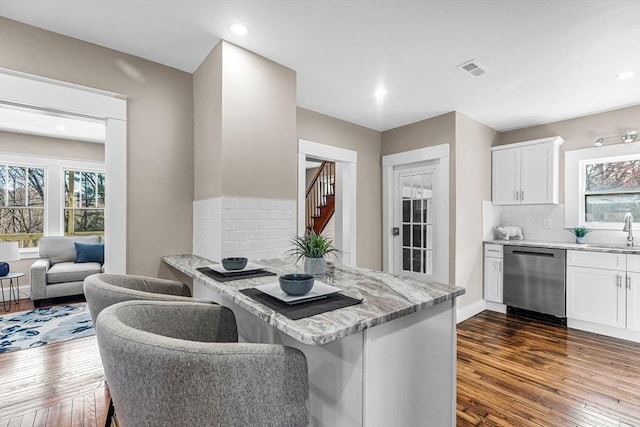 kitchen featuring white cabinets, dishwasher, a sink, dark wood-style flooring, and backsplash