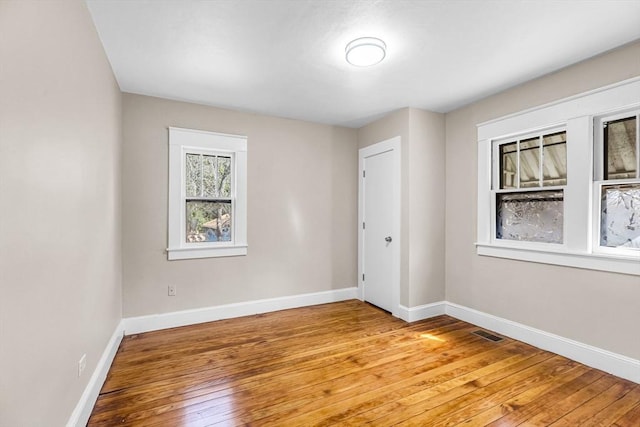 unfurnished room with light wood finished floors, baseboards, and visible vents