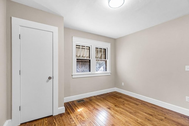 unfurnished bedroom featuring visible vents, baseboards, and hardwood / wood-style floors