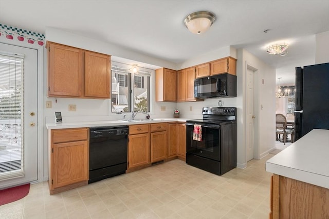 kitchen with plenty of natural light, sink, an inviting chandelier, and black appliances