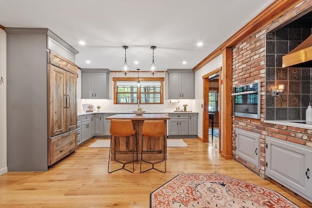 6 N St, Acton, MA 01720 - kitchen with gray cabinetry, paneled refrigerator, a kitchen island, light wood-style floors, and light countertops