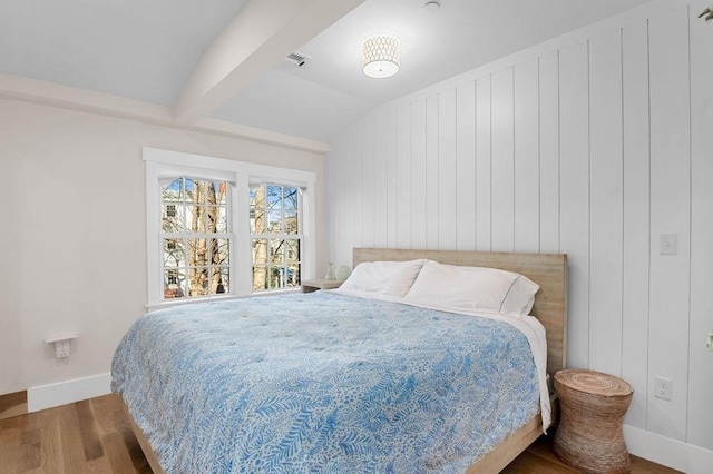 bedroom with vaulted ceiling with beams, baseboards, visible vents, and wood finished floors