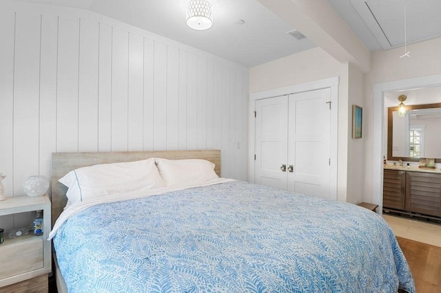 bedroom featuring attic access, a closet, visible vents, and wood finished floors