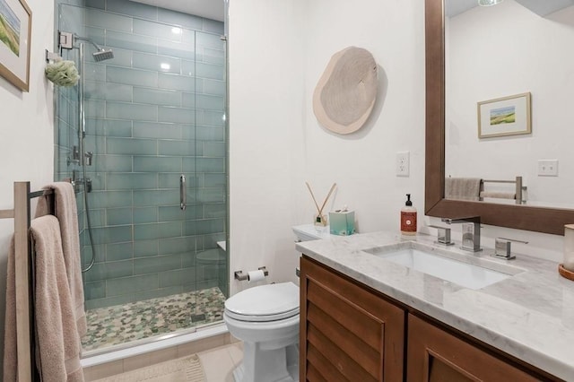 bathroom with a stall shower, vanity, toilet, and tile patterned floors