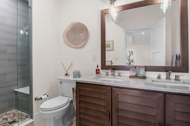 bathroom featuring toilet, a shower stall, double vanity, and a sink