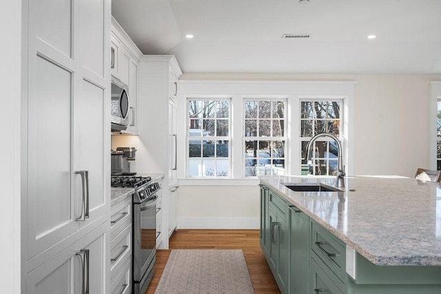 kitchen with visible vents, gas stove, stainless steel microwave, a sink, and recessed lighting